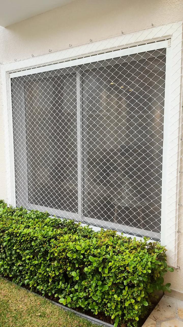 Vista de fora da janela da sala com rede de proteção sob medida.